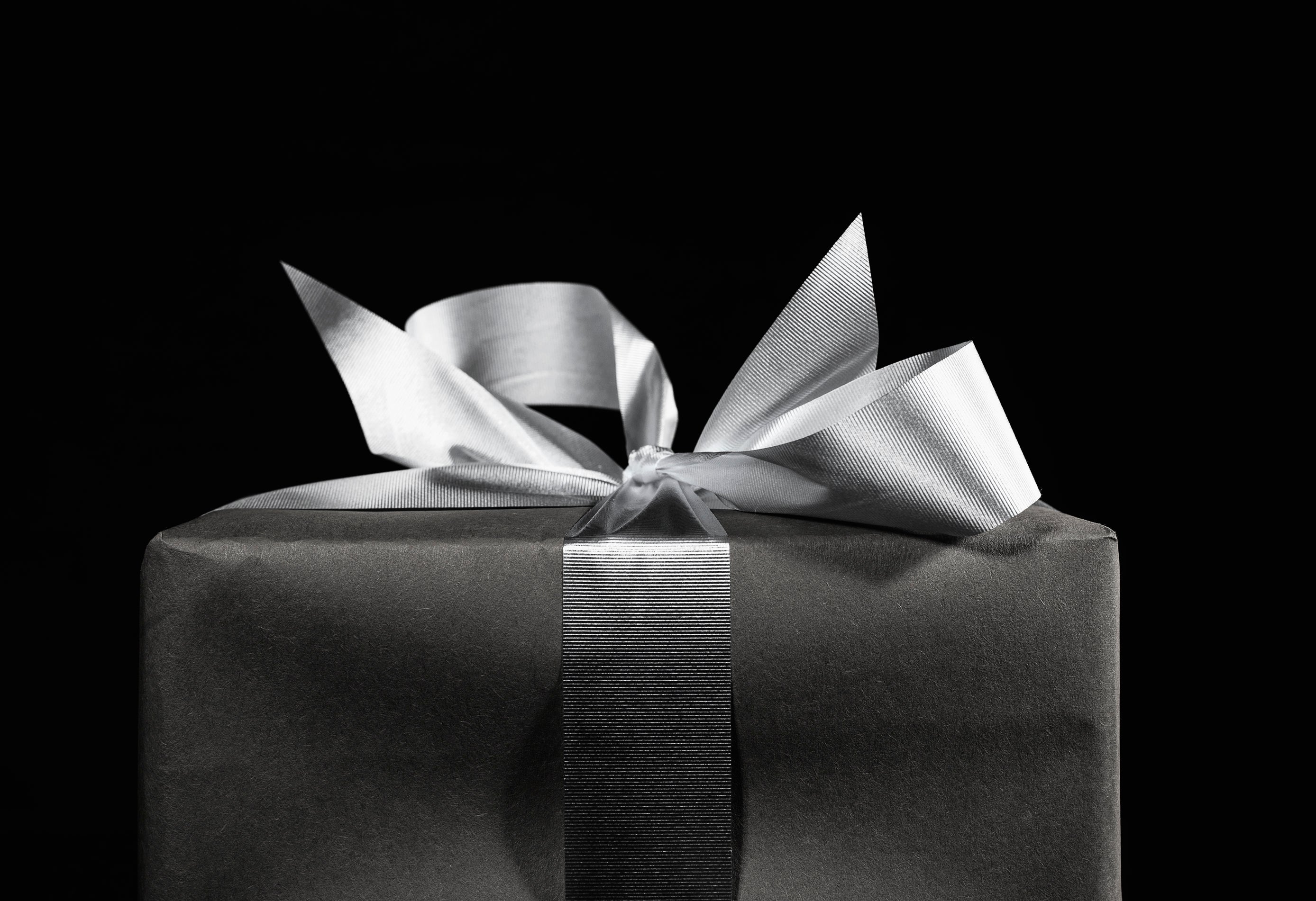 Black-wrapped gift box with a silver satin ribbon and bow