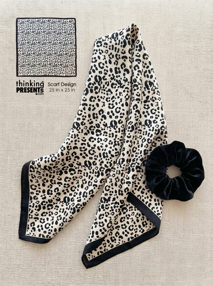 Leopard print scarf and black scrunchie on a beige surface with 'thinking presents' branding.