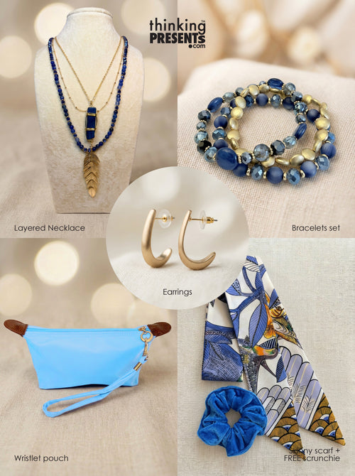 Curated gift set featuring layered gold-tone necklace with blue stone pendant and feather charm, matching blue beaded bracelets, minimalist hoop earrings, light blue wristlet pouch, and a patterned silky scarf with velvet-touch scrunchie, styled as a fresh and vibrant ready-to-gift set