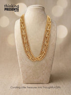 Layered gold chain necklace with mixed link styles and textured details displayed on neutral jewelry stand