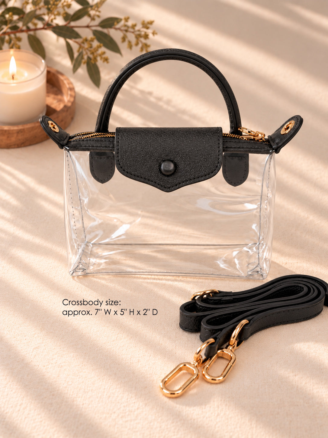 Clear crossbody bag with black flap, top handle and detachable black strap with gold hardware, approx. 7 x 5 x 2 inches