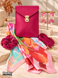 Fuchsia pink vegan crossbody bag with gold push lock, chandelier earrings, silky floral scarf, and berry velvet scrunchie