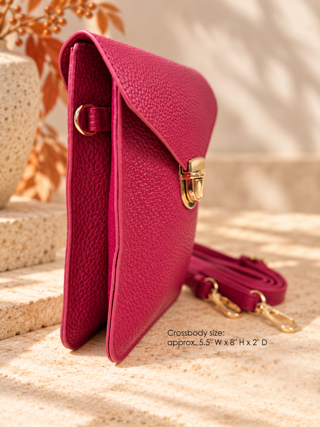 Side view of fuchsia pink vegan crossbody bag with gold hardware and removable strap
