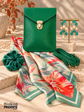 Emerald green vegan crossbody bag with gold push lock, teal and ivory chandelier earrings, silky watercolor floral scarf, and velvet scrunchie