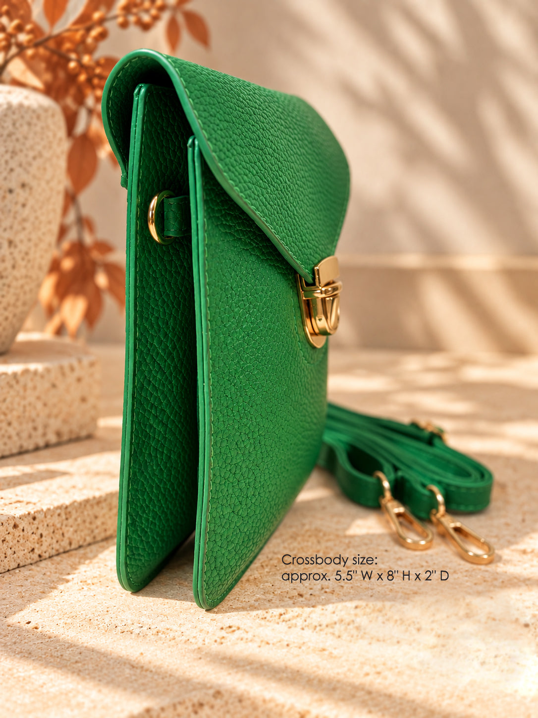Side view of emerald green vegan crossbody bag with gold push lock and removable strap, approx. 5.5 x 8 x 2 inches