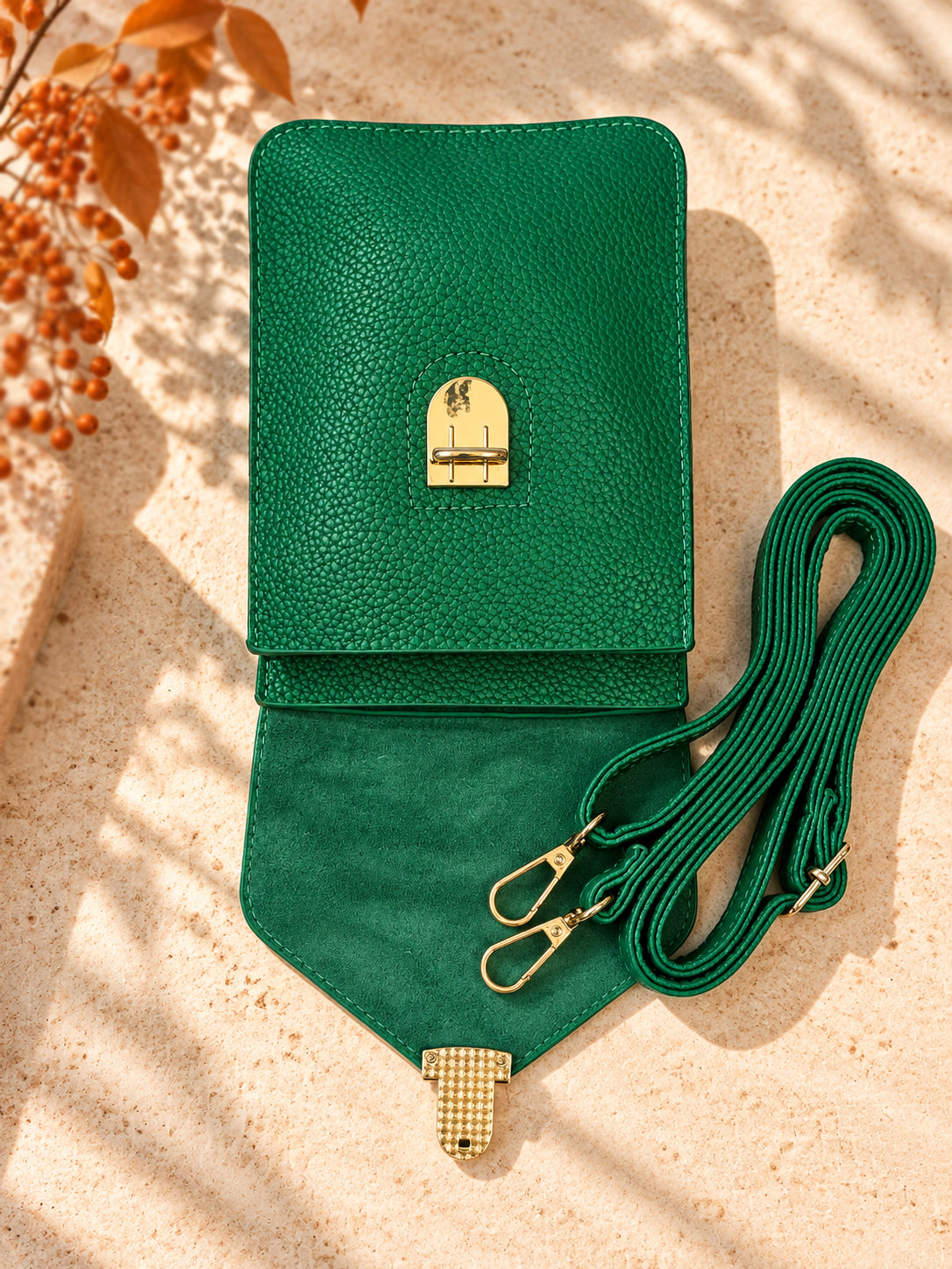 Emerald green crossbody bag open showing soft lined flap, gold turn lock, and adjustable strap