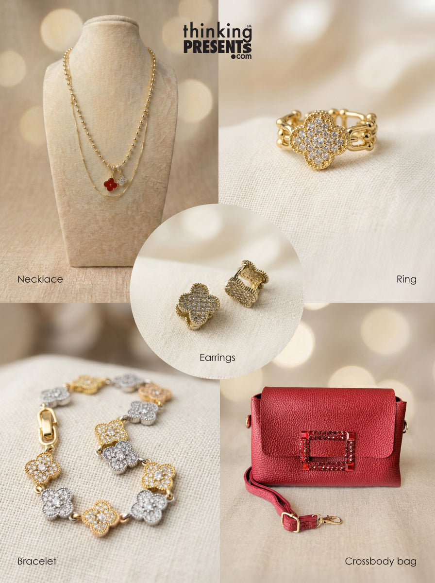 Curated gift set featuring layered gold-tone necklace with clover charms, matching statement ring and stud earrings with pavé detail, coordinating bracelet with mixed metal clover accents, and a red crossbody bag, styled as a bold and elegant ready-to-gift set