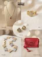 Curated gift set featuring layered gold-tone necklace with clover charms, matching statement ring and stud earrings with pavé detail, coordinating bracelet with mixed metal clover accents, and a red crossbody bag, styled as a bold and elegant ready-to-gift set