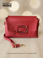 Red handbag with decorative clasp on a beige background, featuring 'thinking Presents' branding.