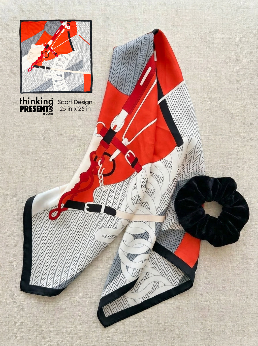 Scarf with equestrian design and a black scrunchie on a beige surface