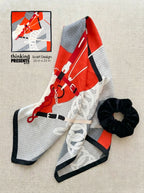 Scarf with equestrian design and a black scrunchie on a beige surface