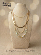 Layered gold-tone necklace with mixed chains and faceted green crystal accents, displayed on a neutral bust, part of the Green Reverie Gift Set by Thinking Presents™