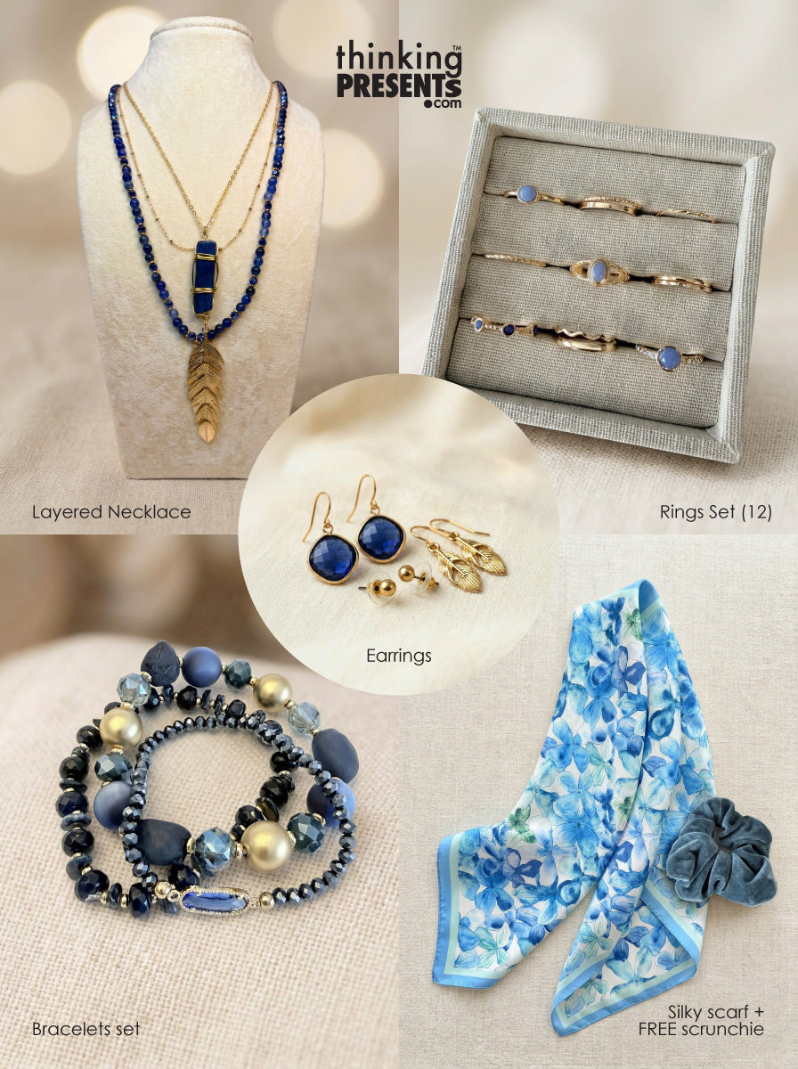Curated gift set featuring layered gold-tone necklace with deep blue stone pendant and feather charm, twelve-piece ring set with blue accents, matching drop earrings, stackable blue beaded bracelets, and a soft floral blue scarf with coordinating scrunchie, styled as an elegant and serene ready-to-gift set