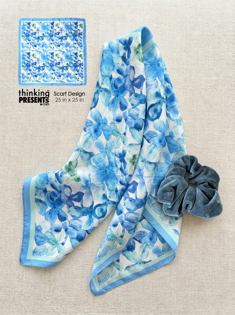 Blue floral scarf with a matching scrunchie on a beige background, featuring 'thinking presents' branding.