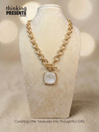 Gold-tone chain necklace with toggle clasp and square ivory pendant, styled on a neutral display, elegant and refined curated gift aesthetic