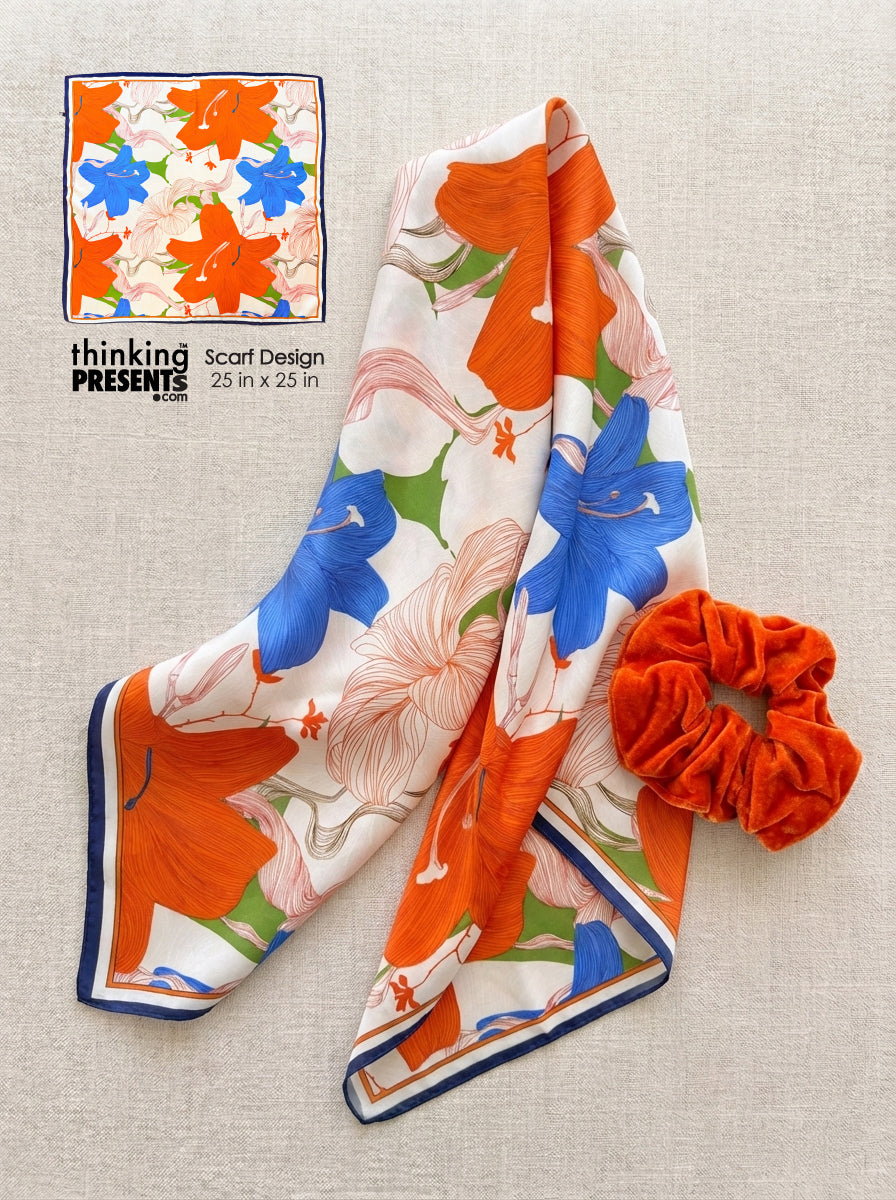 Floral scarf with orange and blue flowers on a beige background, accompanied by a matching scrunchie.