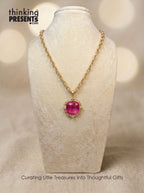 Gold-tone chain necklace with faceted magenta stone pendant and delicate crystal accents, styled on a neutral display, bold and feminine curated gift aesthetic