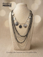 black and silver necklace set on a mannequin bust with 'thinking PRESENTS' branding.