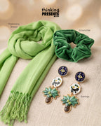 Green scarf, scrunchie, and earrings on a beige surface with 'thinking PRESENTS' branding.