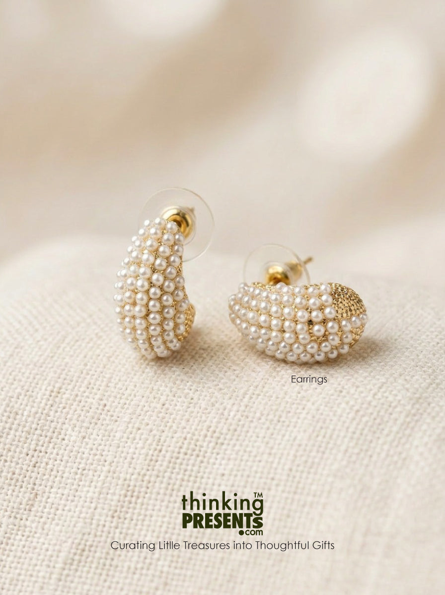Pearl bead cluster earrings with gold-tone posts, displayed on a textured beige fabric background. The brand name 'thinking PRESENTS' is visible at the bottom of the image.