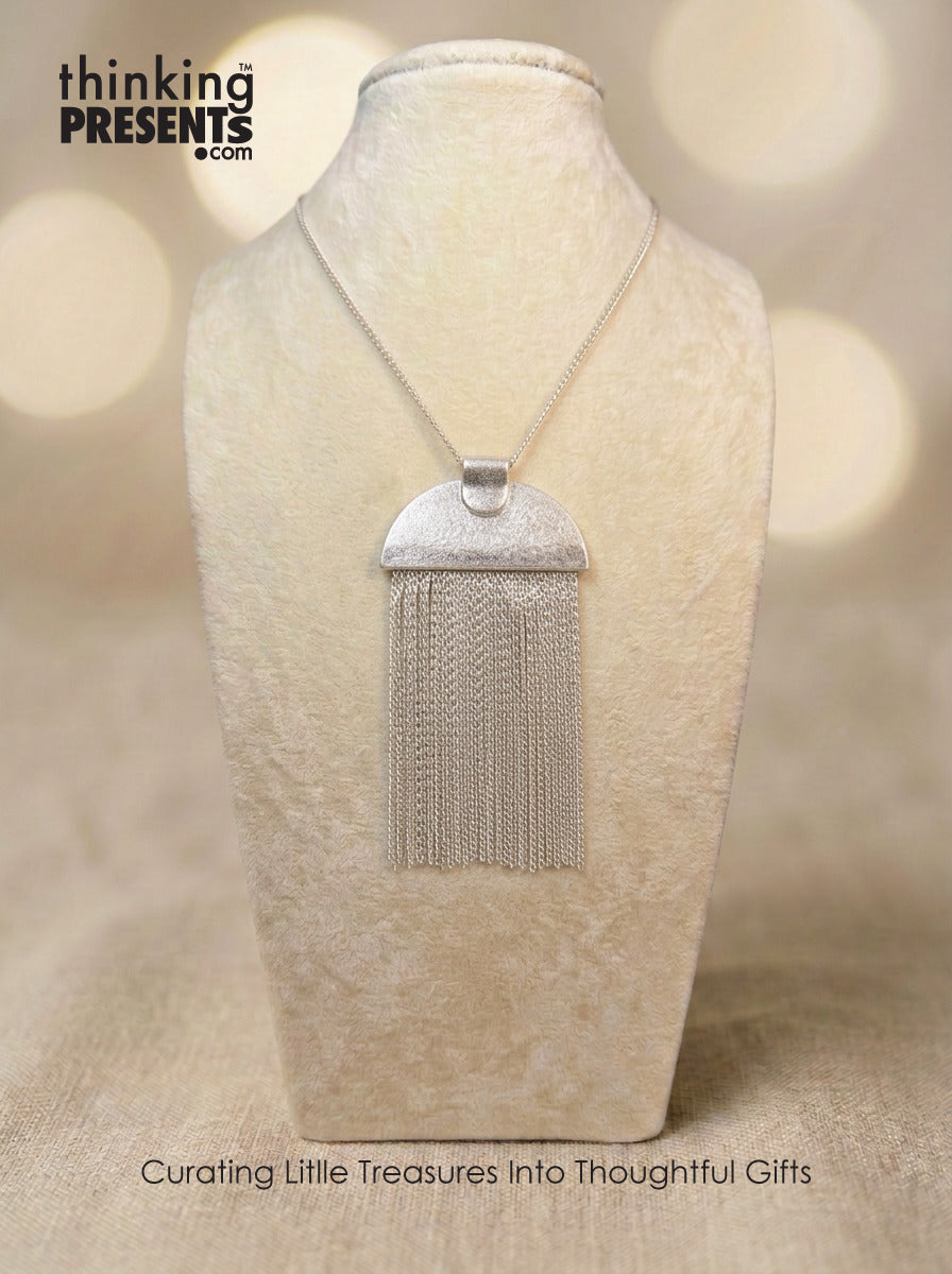 Silver fringe necklace on a mannequin bust with a blurred background and 'thinking PRESENTS' branding.