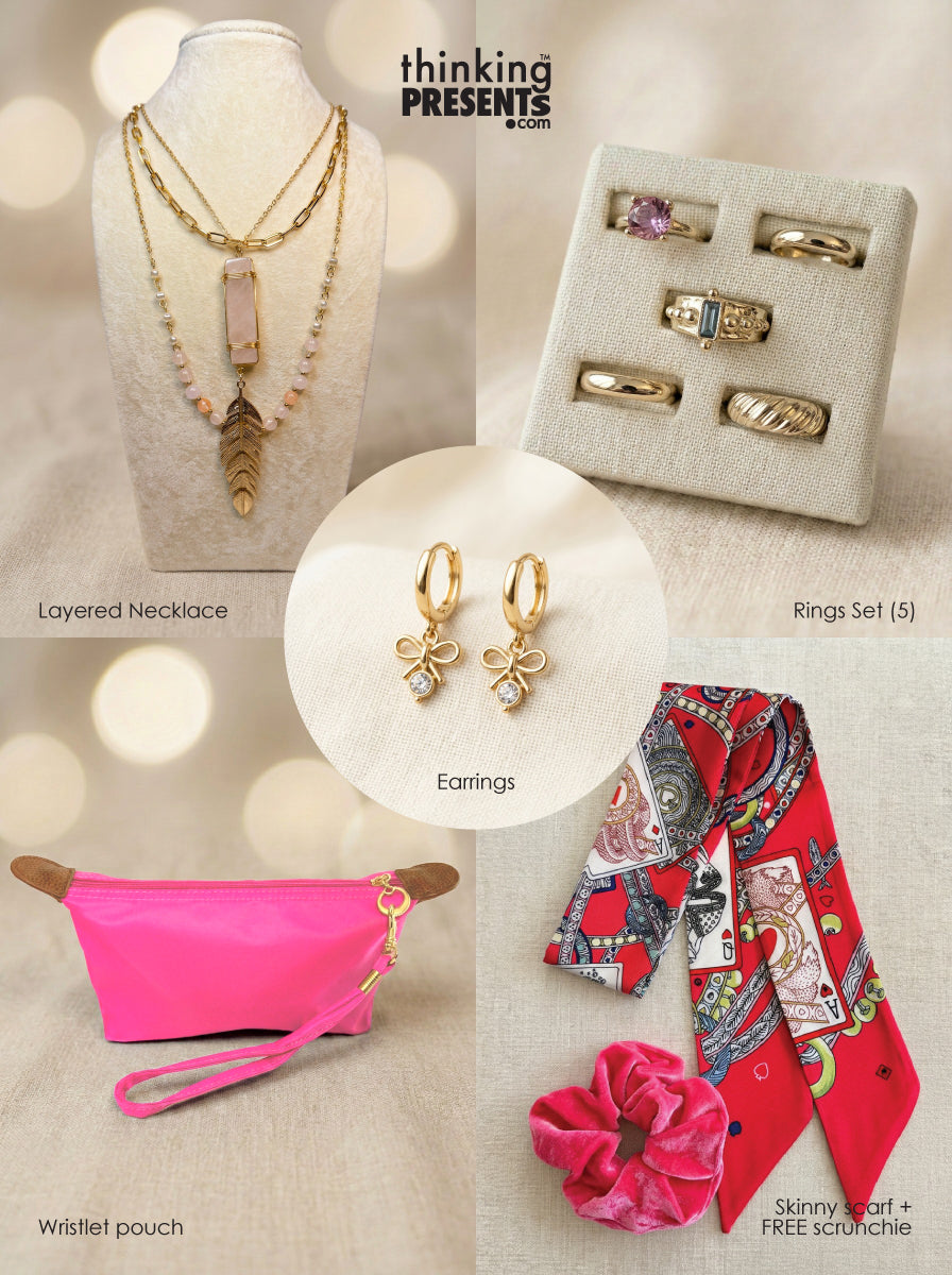 Curated gift set featuring layered gold-tone necklace with pink stone pendant and feather charm, matching hoop earrings with bow detail, five-piece ring set with mixed designs, bright pink wristlet pouch, and patterned red skinny scarf with matching scrunchie, styled as a bold and feminine ready-to-gift set