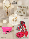 Curated gift set featuring layered gold-tone necklace with pink stone pendant and feather charm, matching hoop earrings with bow detail, five-piece ring set with mixed designs, bright pink wristlet pouch, and patterned red skinny scarf with matching scrunchie, styled as a bold and feminine ready-to-gift set