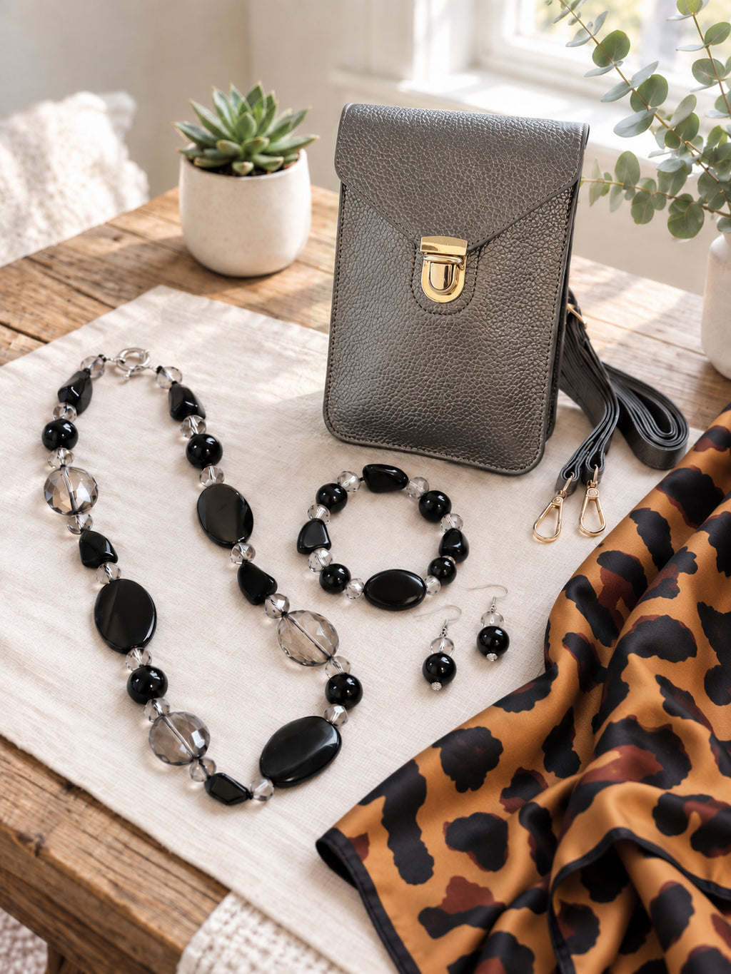 The Pewter Chic Edit curated set by Thinking Presents with pewter crossbody bag, black stone necklace, bracelet, earrings and leopard-print scarf