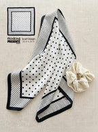Black and white polka dot scarf with a matching scrunchie on a beige background
