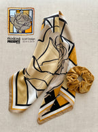 Scarf with abstract design and scrunchie on a textured surface, featuring 'thinking presents' branding.