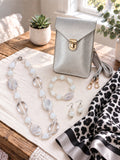 The Silver Chic Edit curated set by Thinking Presents with silver crossbody bag, white stone necklace, bracelet, earrings and leopard-print scarf