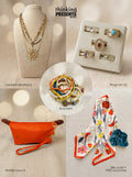 Curated gift set featuring layered gold-tone necklace with sun pendant, five-piece ring set with colorful stones, stackable beaded bracelets, vibrant orange wristlet pouch, and floral silky scarf with teal scrunchie, styled as a bold and playful ready-to-gift set