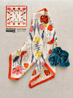 Floral scarf and blue scrunchie on a textured surface with 'thinking presents' branding.