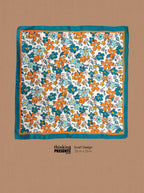 A square scarf laid flat on a tan background, featuring a retro floral pattern with orange and teal flowers on a white base, finished with a teal border. Text below reads 'thinking PRESENTS SCARF DESIGN 25 in x 25 in'.