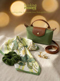 Green handbag with matching scarf, scrunchie, and earrings on a neutral background with 'thinking presents' branding.