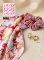 Floral scarf, pink scrunchie, and gold earrings on a beige surface with a small inset of a product label.