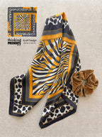 Patterned scarf with a scrunchie on a textured surface, featuring 'thinking presents' branding.