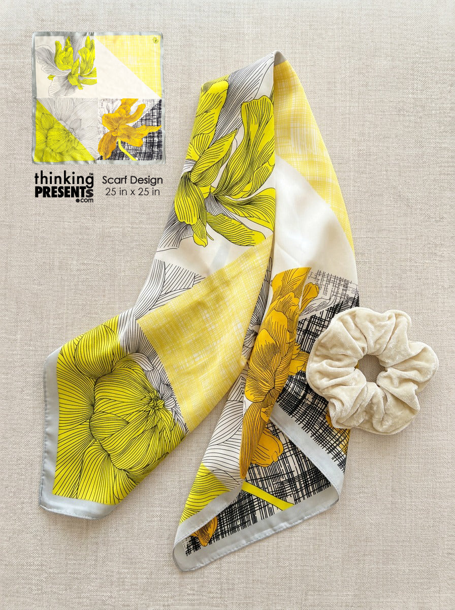 Floral scarf with a scrunchie on a textured surface, featuring 'thinking presents' branding.